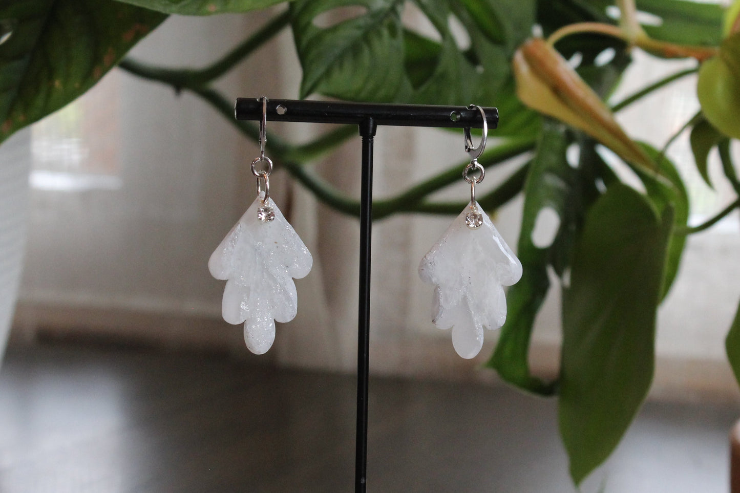 White Marble Scallops earrings with cz charm and stainless steel hooks displayed on black stand with green plant background