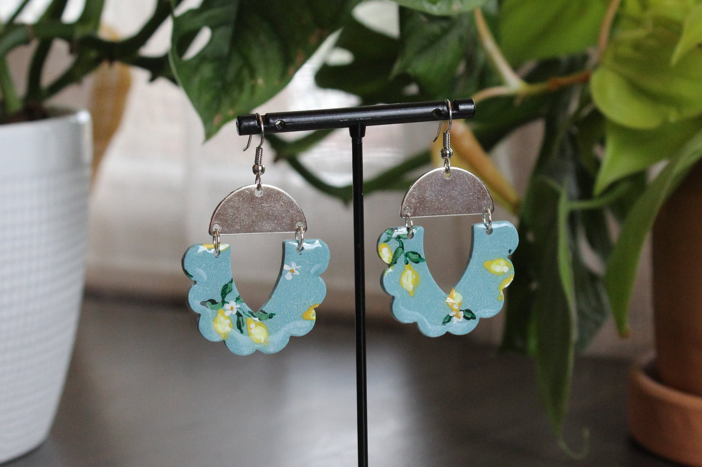 Lemon Arches hand painted lemon earrings on nickel free ear wires with 2.5 inch drop displayed on black stand