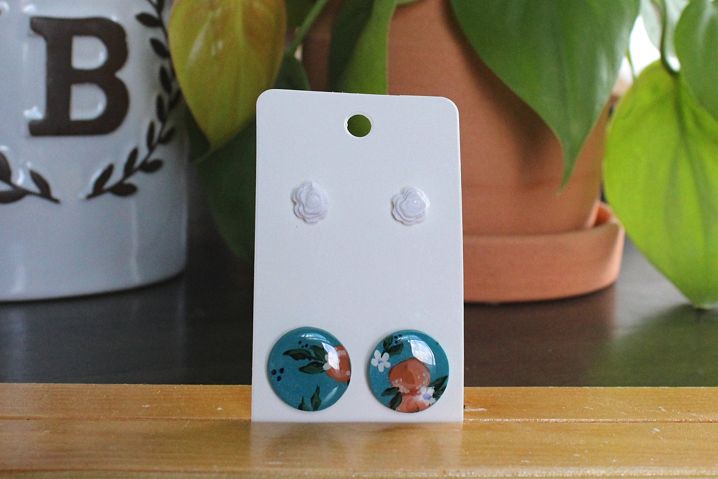 Orange studs hand painted with white rose studs on stainless steel posts displayed on a white card.