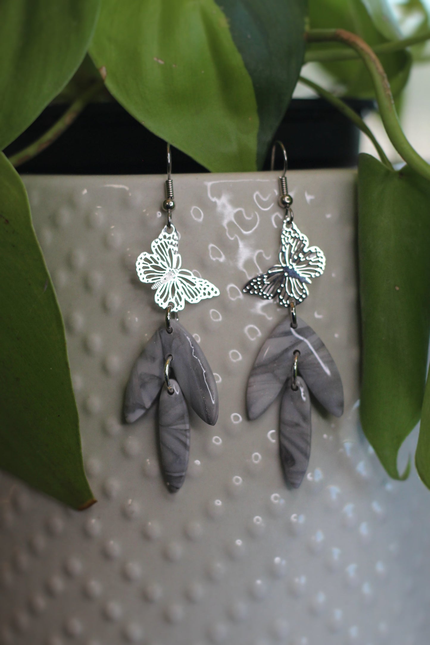 Gray marble butterfly earrings with silver charms and leafy dangles on nickel-free hooks