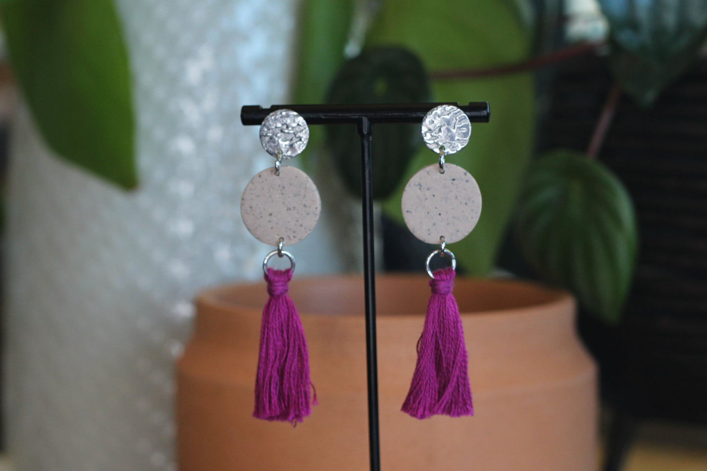 Speckled beige and magenta tassel earrings with silver posts on display stand